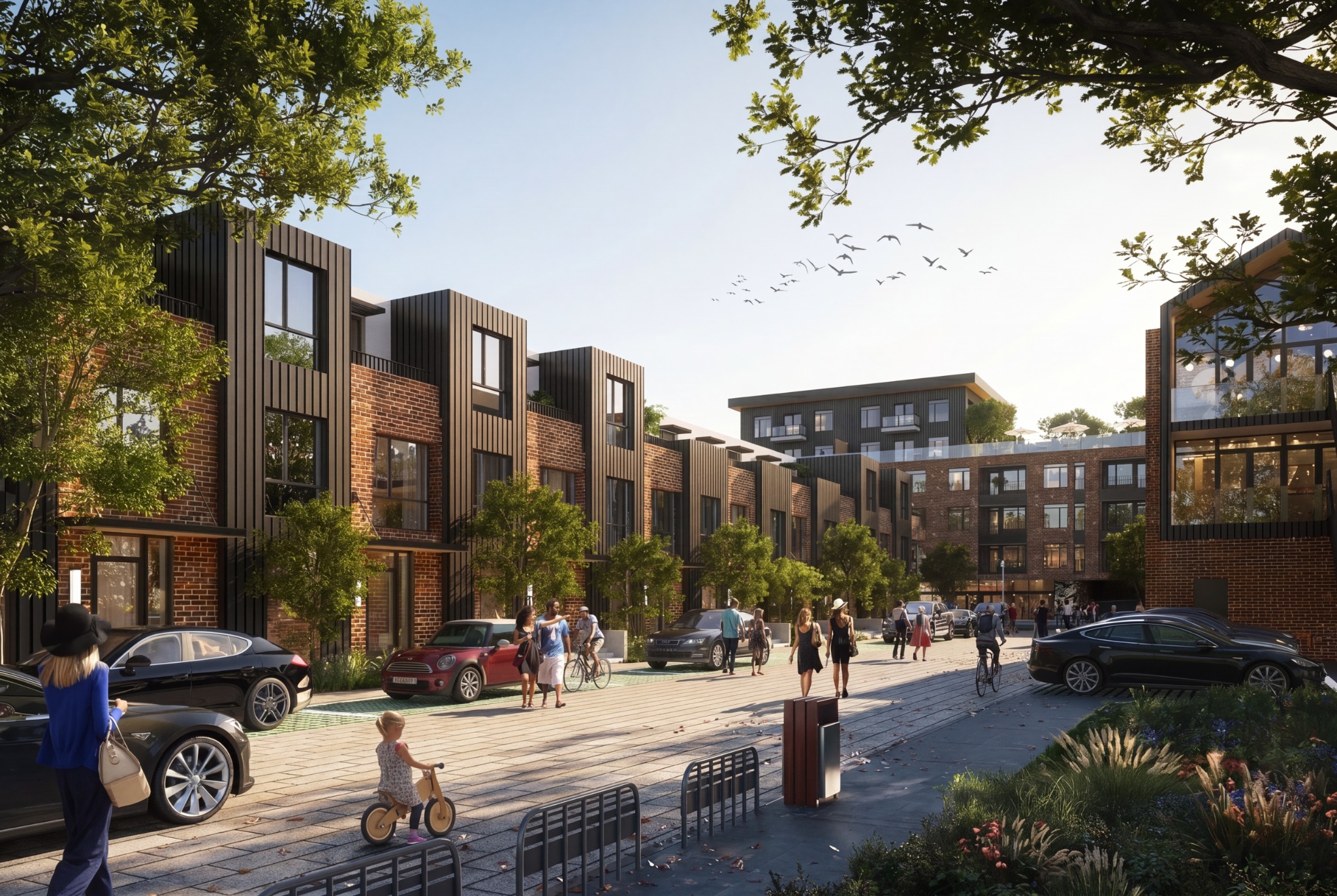 Brick and dark metal townhomes framing a street with pedestrians and bicycles