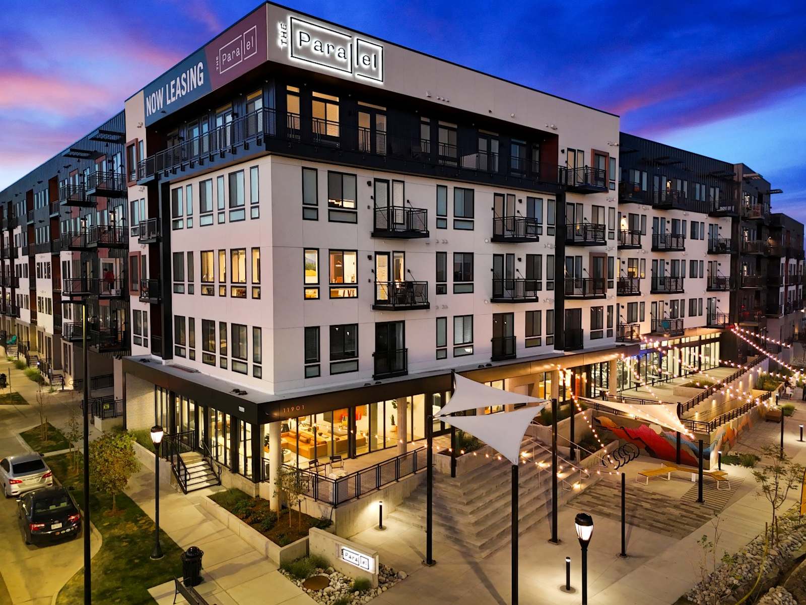The Parallel's completed exterior at twilight, with balconies and an illuminated outdoor terrace
